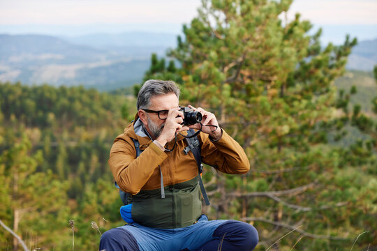 Man taking photos on a mountain with his camera