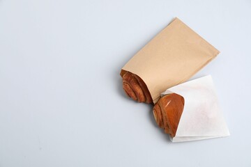 Paper bags with freshly baked buns on white background, top view. Space for text