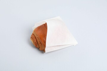 Paper bag with freshly baked bun on white background