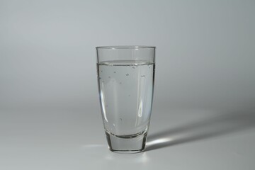 Refreshing soda water in glass on grey background