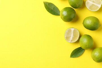 Fresh limes and leaves on yellow background. Space for text