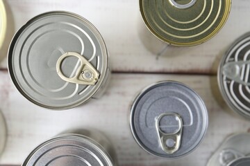 Many closed tin cans on white wooden table, flat lay