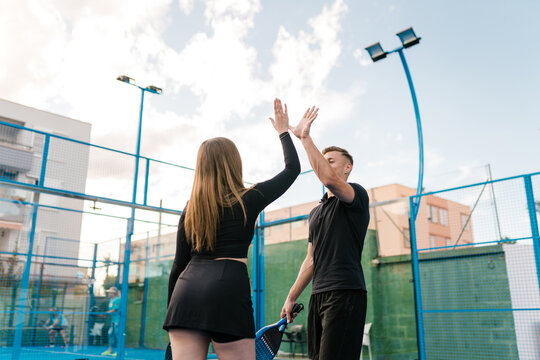 Padel players giving high five after winning match