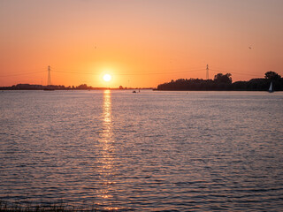 Sunset over a canal with boats on the water. Dutch landscape.

