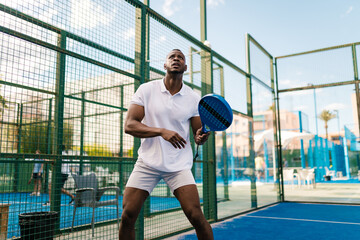 Paddle tennis player watching the ball during a match on a sunny day