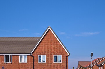 Clear blue sky above a suburban house with a triangular roof