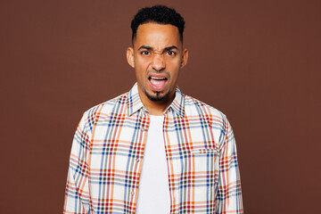 Young sad mad shocked angry outraged dissatisfied man of African American ethnicity he wear blue shirt casual clothes look camera isolated on plain brown background studio portrait. Lifestyle concept.