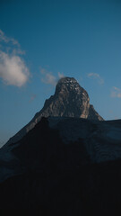 Iconic Matterhorn peak stands tall beneath drifting clouds, epitomizing Swiss alpine grandeur.
