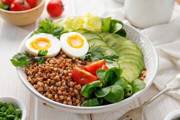 Buckwheat groats with avocado, various vegetables and soft-boiled egg, focus on groats, close up view. Healthy breakfast suggestion slavic girl diet
