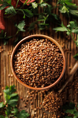 Common roasted brown buckwheat in a wooden bowl, top view