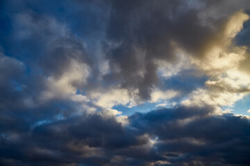 Sun rays break through gray clouds against a blue winter sky.