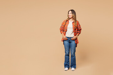 Young smiling happy cheerful positive satisfied woman she wear orange shirt casual clothes look aside on area mock up isolated on plain pastel light beige background studio portrait Lifestyle concept