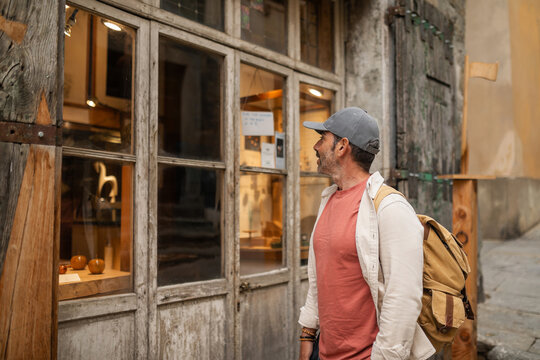 man looking at a shop window in a town in tuscany, italy