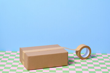 Cardboard Box with Tape on Colorful Checkered Background