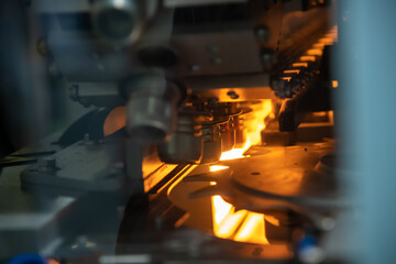 Close-up view of empty modern automatic rotary wheel PET (or plastic) bottle blow moulding machine with orange light working in factory. Soft focus. Copy space. Drink technology theme.