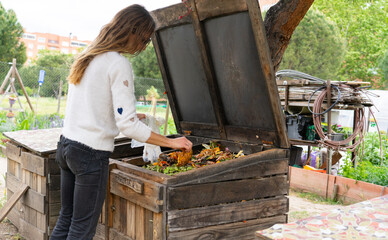 Woman composting food scraps in garden compost bin