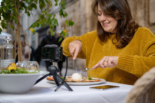 Woman blogger eating pizza in the restaurant and recording her vlog