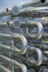 Close-up view of parts and pipes of milk ultra-pasteurization (or ultra-high temperature processing) machine. Industrial background. Soft focus. Copy space. Food and drink processing equipment theme.	