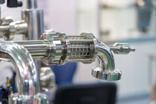 Close-up view of tap on pipe of beverage ultra-pasteurization (or ultra-high temperature processing) machine. Industrial background. Soft focus. Copy space. Food and drink processing equipment theme.