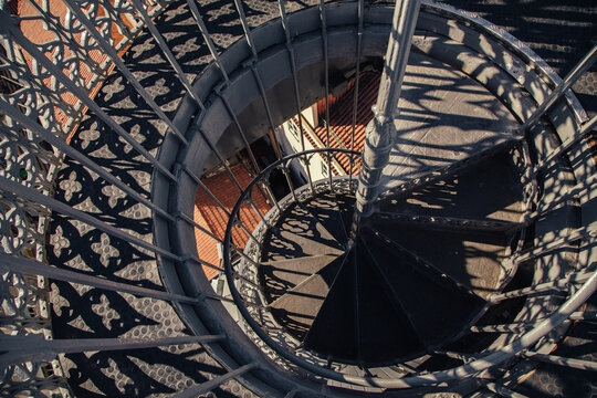 Spiral staircase with intricate shadow patterns in bright sunlight