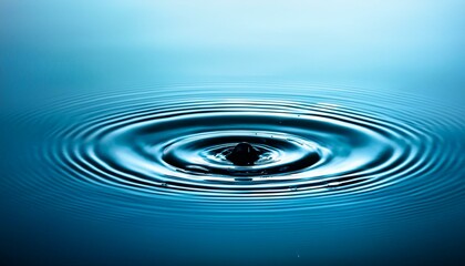 Water droplet creating ripples in still blue water.