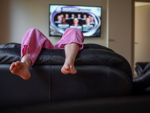 Young girl's bare feet over the back of the couch