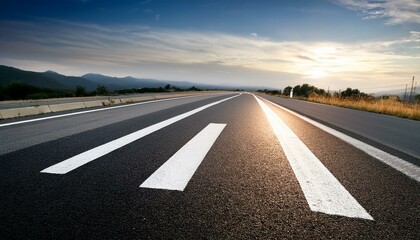 Naklejka premium Asphalt road at sunset with mountains in the background.