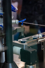 Close-up view of modern coffee pods making machine. Group of blue coffee capsules moves on narrow conveyer belt. Soft focus. Copy space. Coffee manufacturing plant theme.