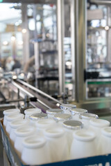 Sealed and open containers of milk are arranged neatly in a factory setting, surrounded by advanced machinery. The environment reflects a focus on hygiene and efficiency.