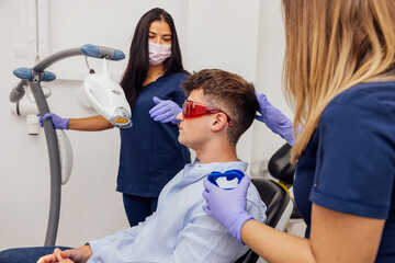 Modern dental clinic teeth whitening procedure with patient