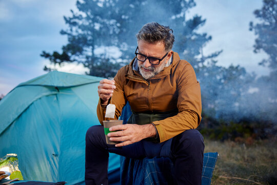 Relaxed man enjoys tea at the campsite