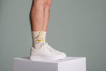 Man Wearing White Sneakers and Colorful Socks on Pedestal