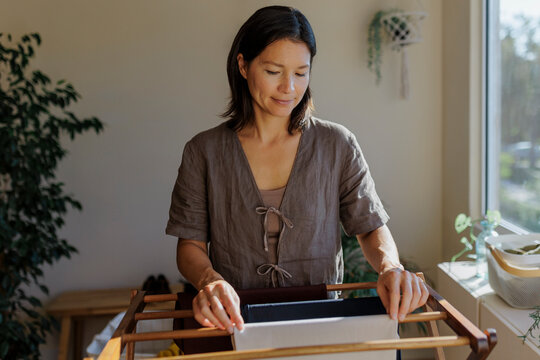 Woman hanging clothes on drying rack at home