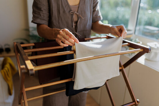 Woman hanging clothes on wooden drying rack