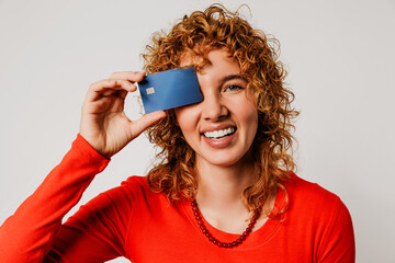 Smiling woman holding credit card over eye on white background