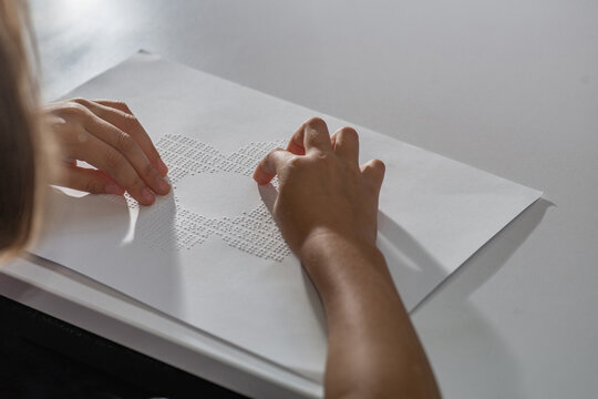 Hands of a little blind child recognizing a picture in Braille