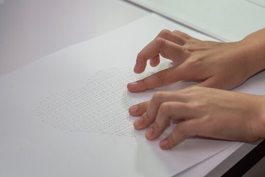 Hands of a little blind child recognizing a picture in Braille