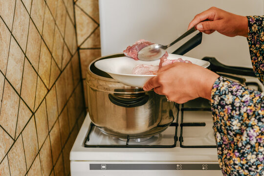Female hands adding lamb cuts into a pressure cooker