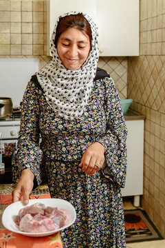 Afghan woman holding a plate with lamb to cook Kabuli Pulao 