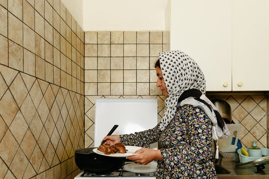 Afghan woman putting cooked lamb on a plate 