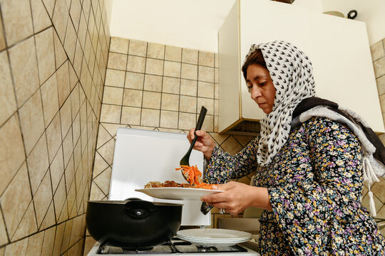 Afghan woman putting on a plate traditional Kabuli Pulao