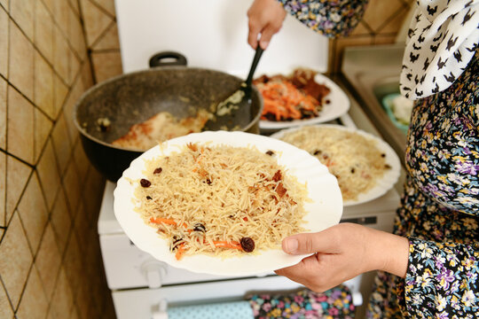 Female hands putting on a plate traditional Kabuli Pulao