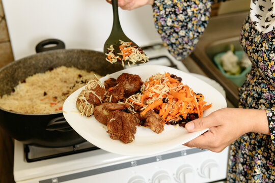 Female hands putting on a plate traditional Kabuli Pulao
