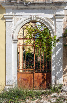 Old entrance with iron gate overgrown with grass and plants
