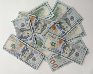 A pile of one hundred dollar bills on a white surface. Cash, money, wealth, finance concept.