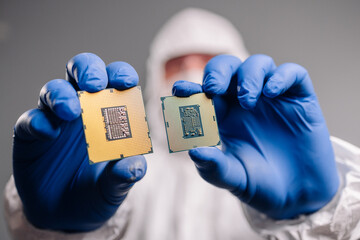 Engineer in a sterile suit inspects and compares two processors in hand, showcasing precision,...