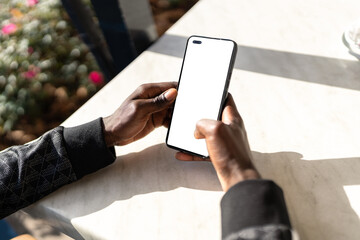 Close-up of man browsing smartphone with blank screen at table in cafe