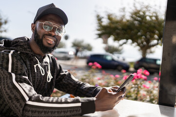 Stylish man using smartphone at outdoor cafe