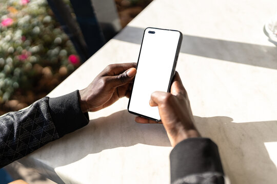 Close-up of man browsing smartphone with blank screen at table in cafe