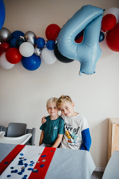 two young kids at superhero-themed party with big blue balloon.
